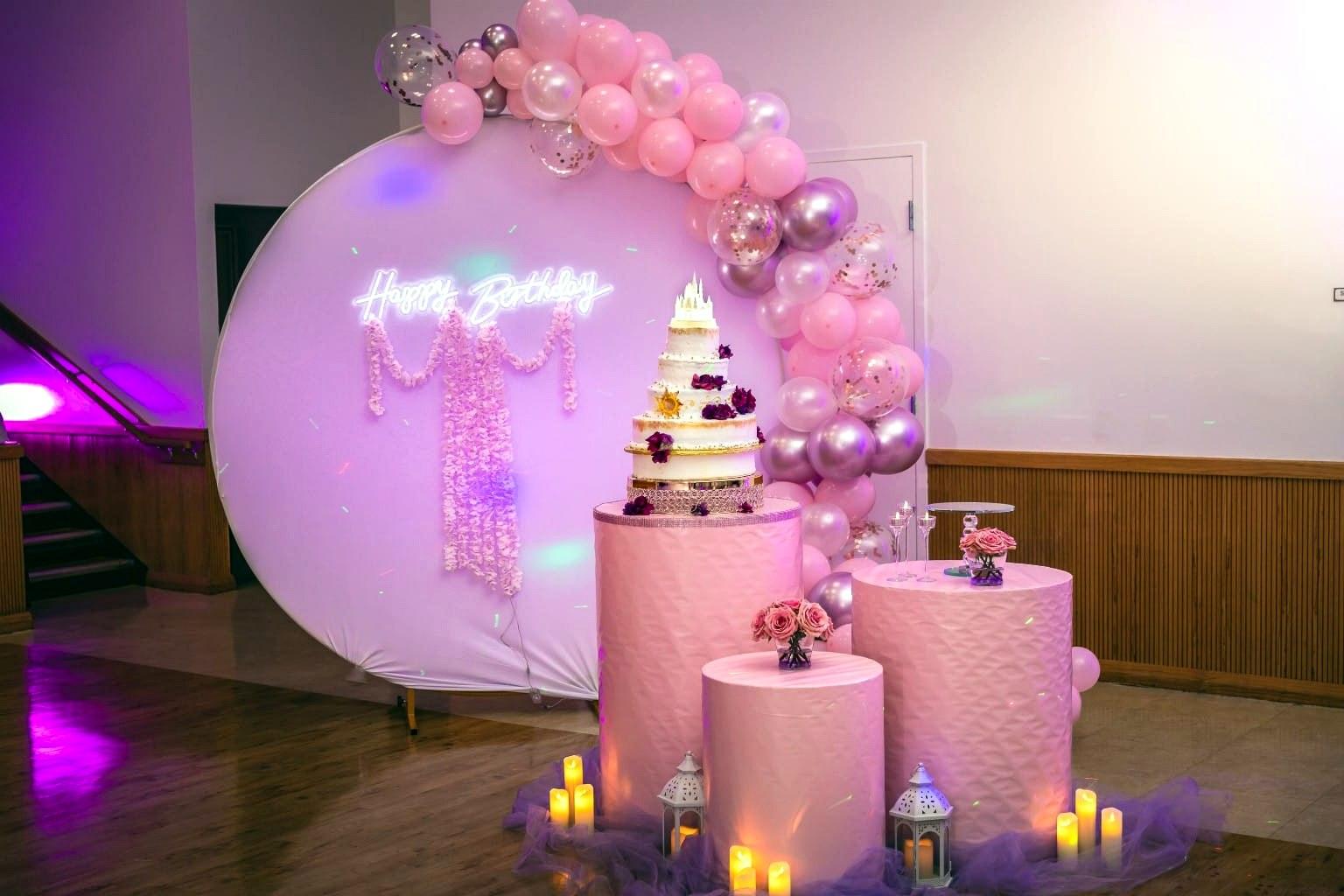 Birthday cake table with a neon sign and balloons